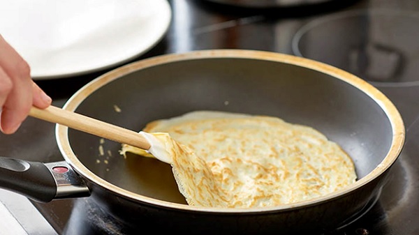 A pancake being fried in a pan
Description automatically generated