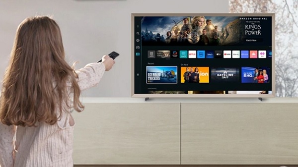 A child holding a remote control and watching television

Description automatically generated