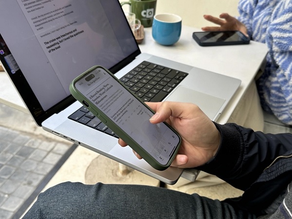 A person holding a phone in front of a computer

Description automatically generated